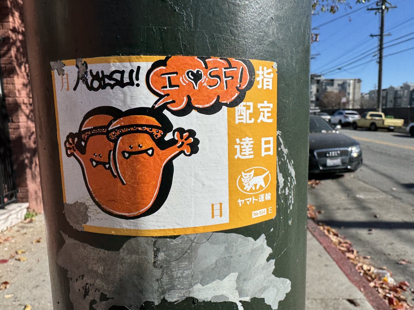 A yellow and white sticker with hand drawn art by Matsu on top. It’s a drawing of a two-headed mushroom saying “I Love SF”. The mushroom has little arms and faces and sharp fangs for teeth.