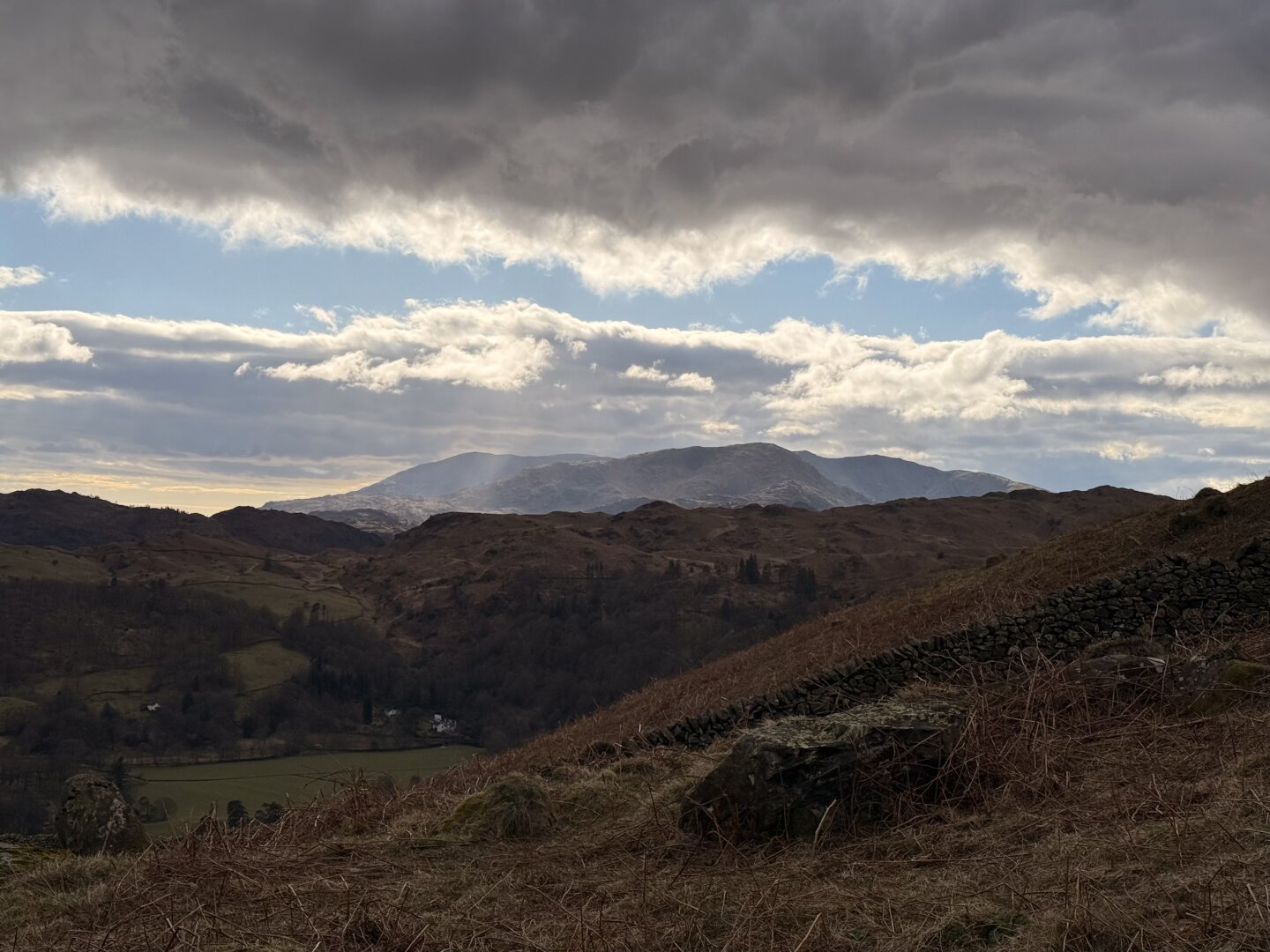 The Langdale pikes lit by sunlight from a gap in the clouds above