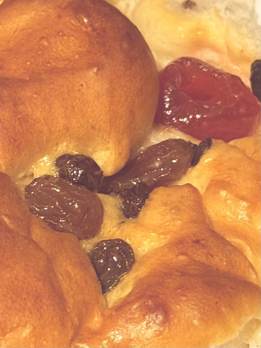 A golden bun embedded with currants and cherries