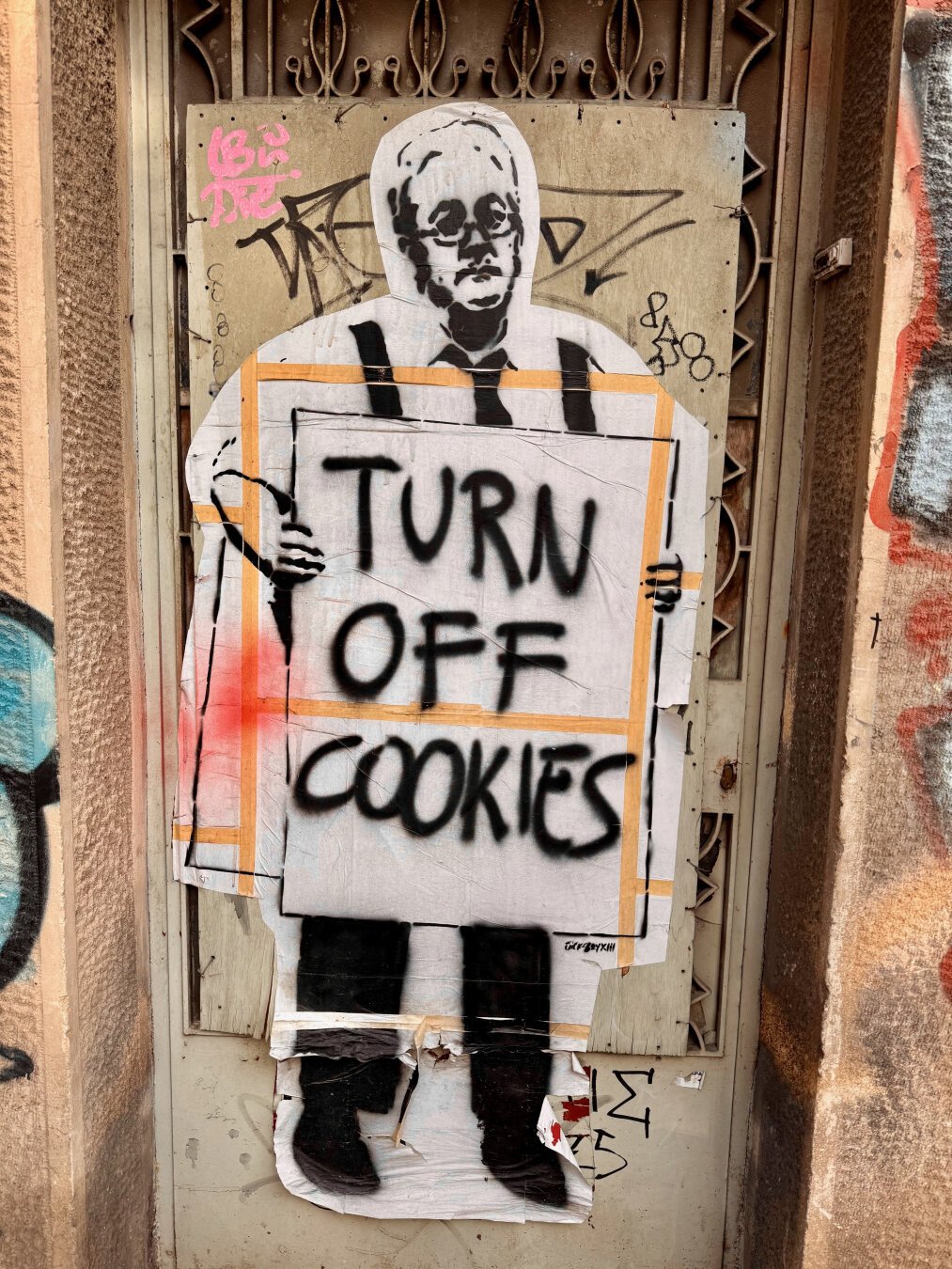 Stencil art of a middle aged man wearing a sandwich board reading 'TURN OFF COOKIES'