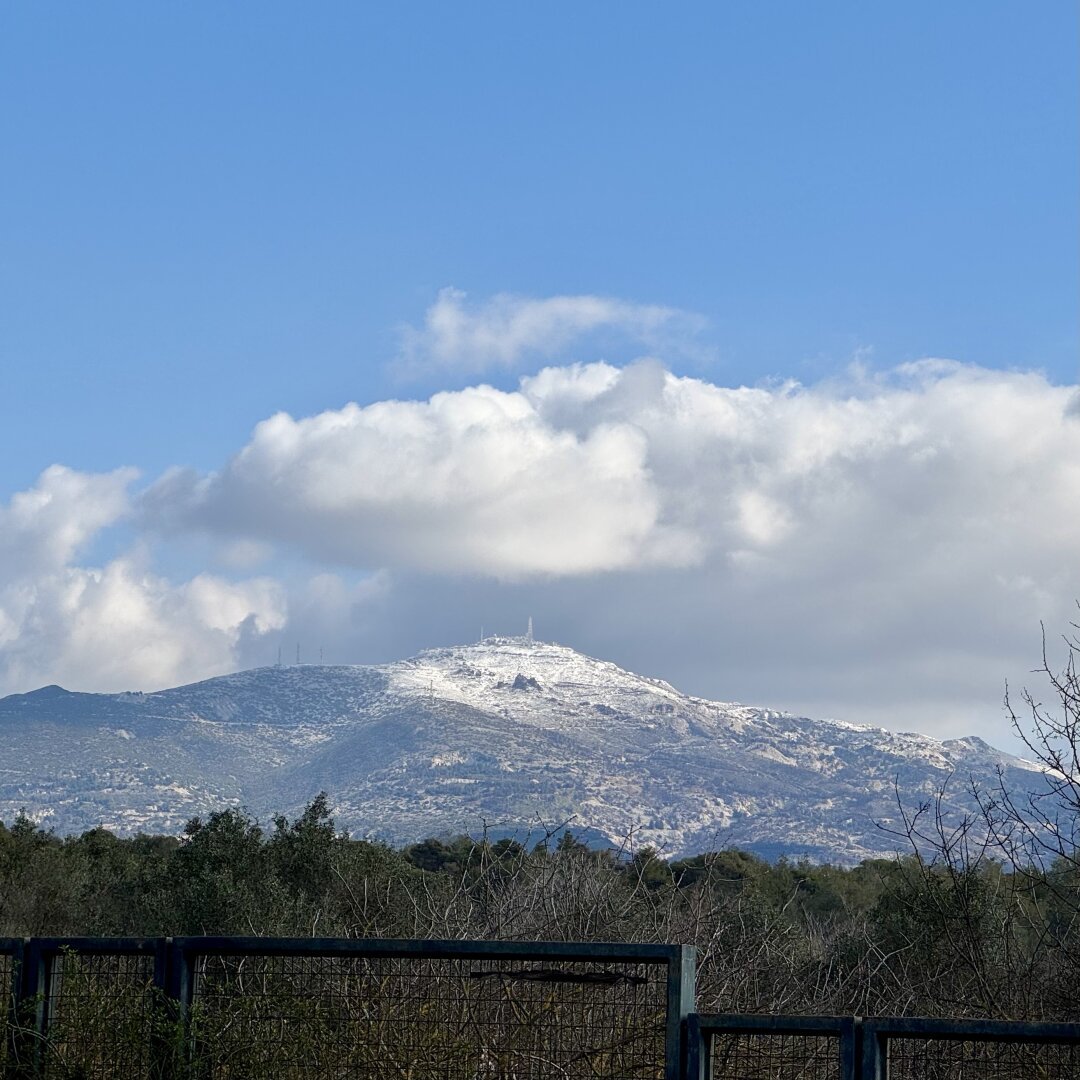 A mountain in the distance with a dusting of snow against blue sky