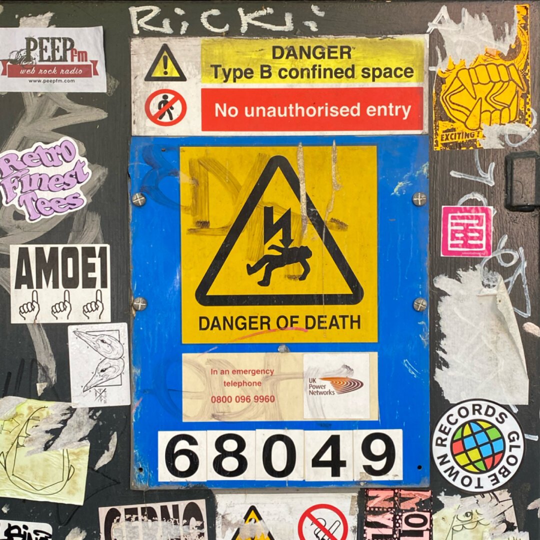 Danger of death sign in the middle of vibrant stickers and other graphic elements.