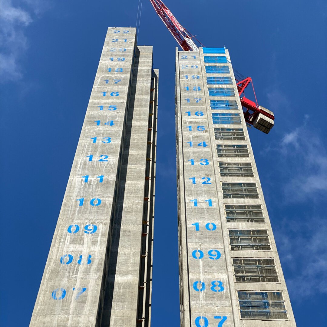 Perspective shot of a building under construction with sequentially numbered floors towering above.