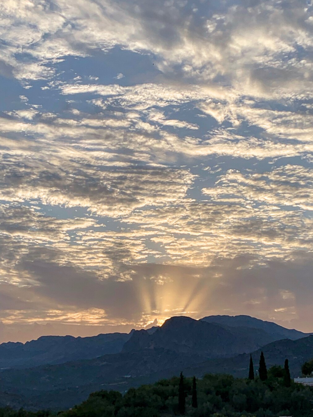 Atardecer tras una montaña en la que destacan los rayos del sol.