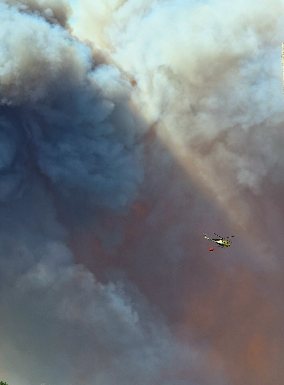 Tiny firefighter helicopter compared to big smoke clouds on background.
Helicoptero de bombeiros pequeno comparado cos nubes de fume do fondo.