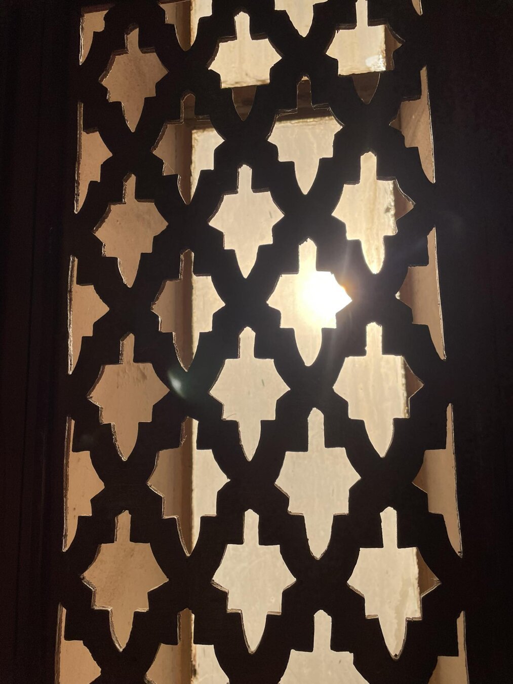 a wooden window frame with various decorations, the photo was taken against the sun, it has very warm colors