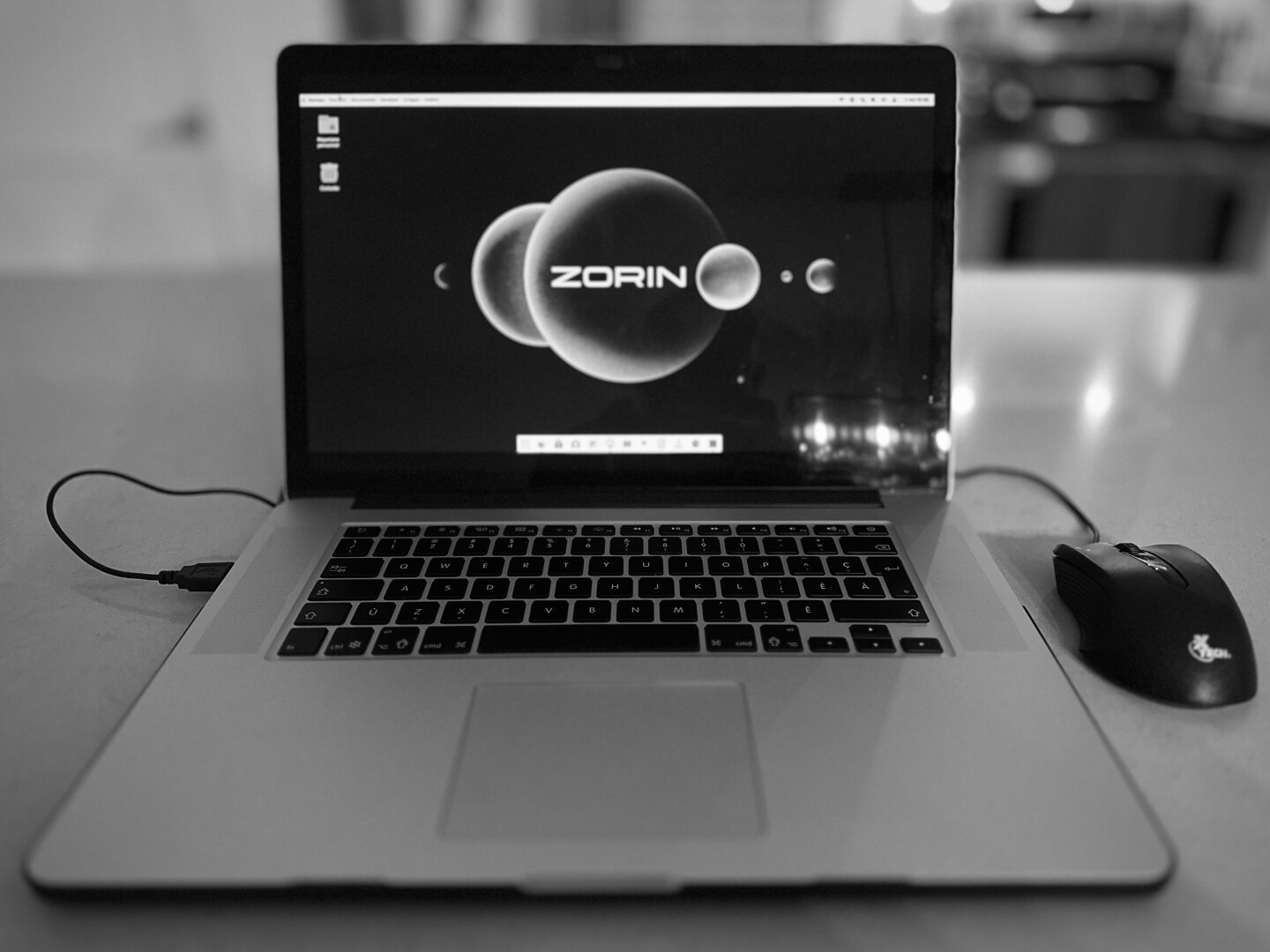 Black and white photo of a MacBook Pro showing a Zorin OS wallpaper.