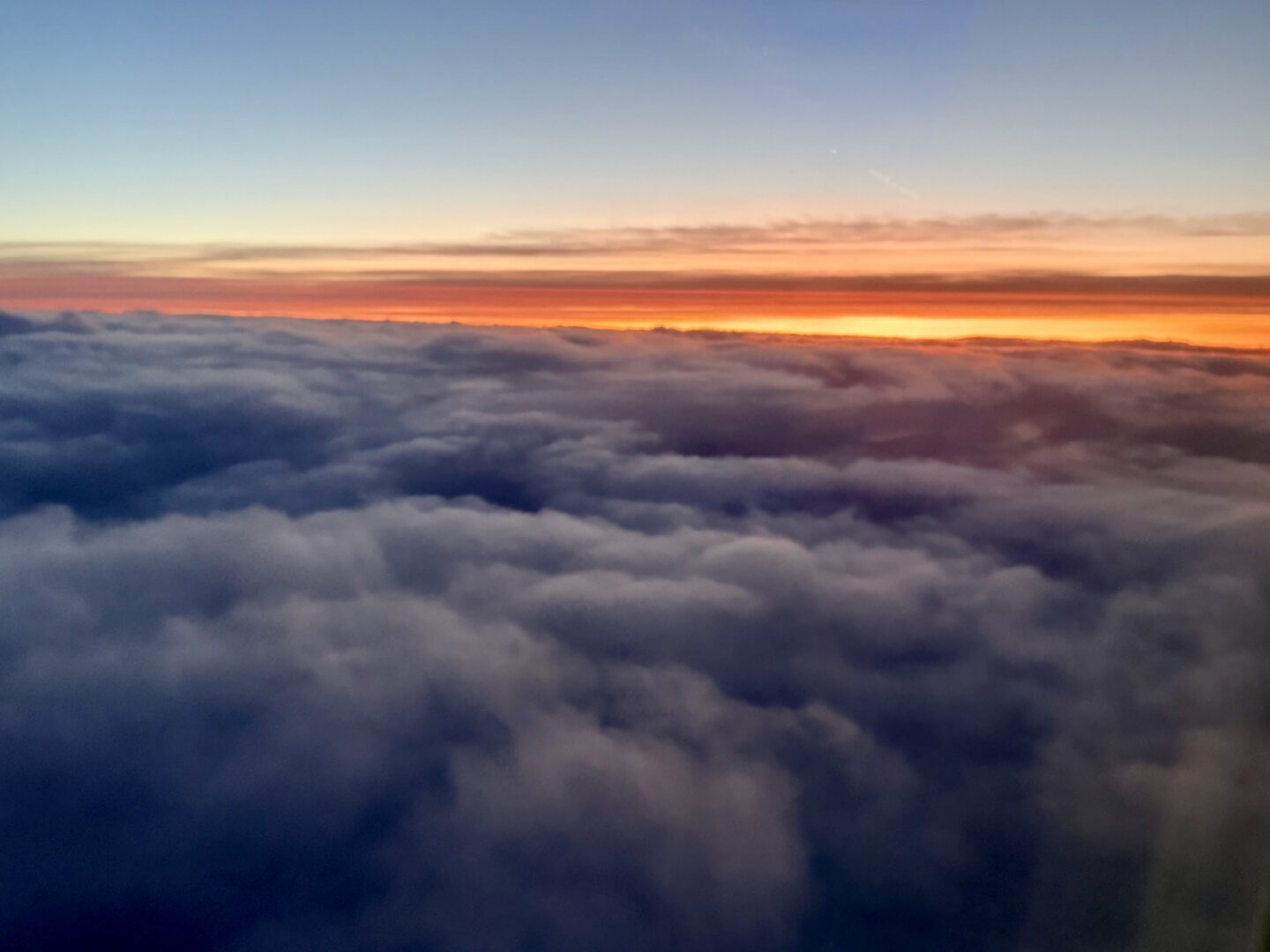 Pillows of clouds with a pretty sunset in the distance
