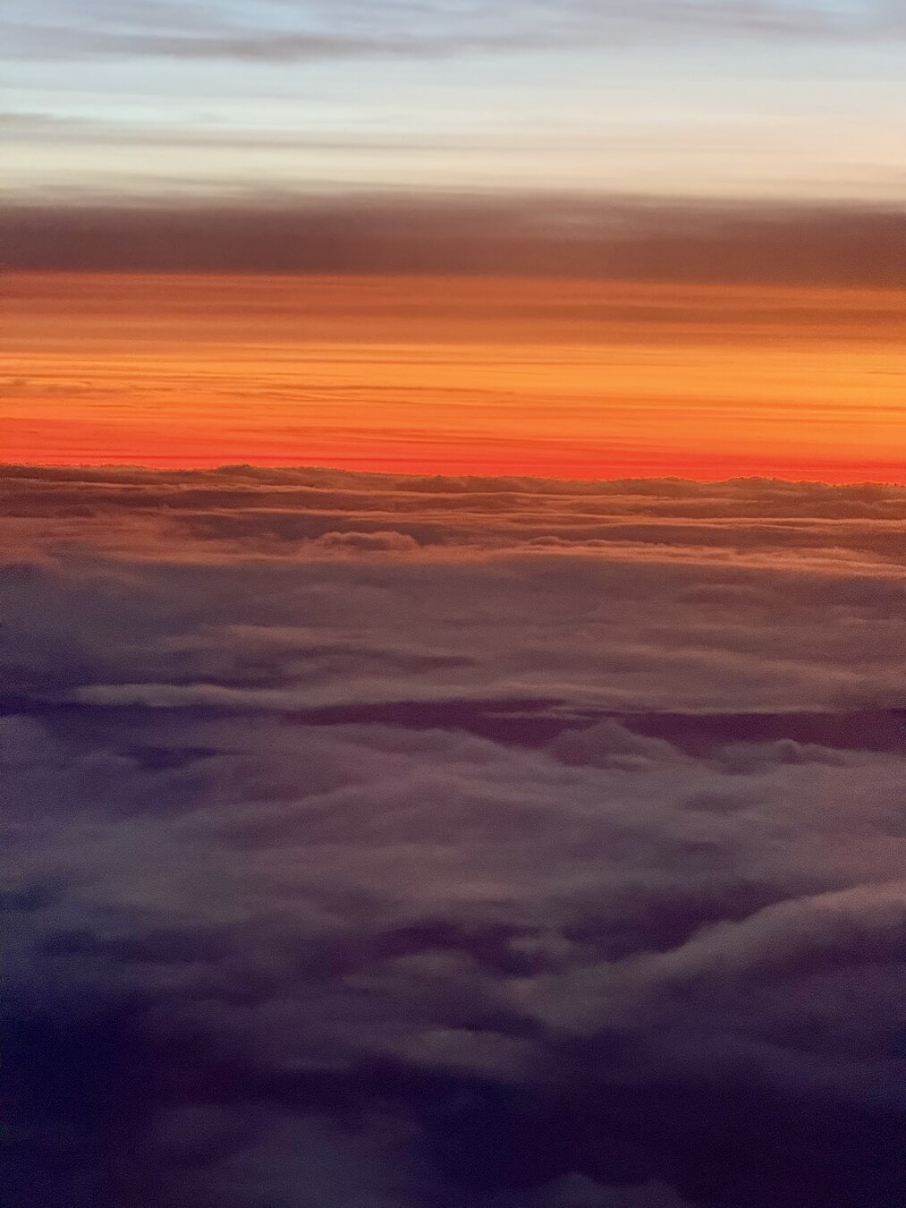 A bright orange red sunset above the clouds