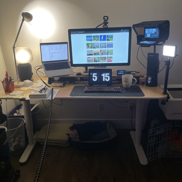 Computer and monitor on a work desk, surrounded by lights.