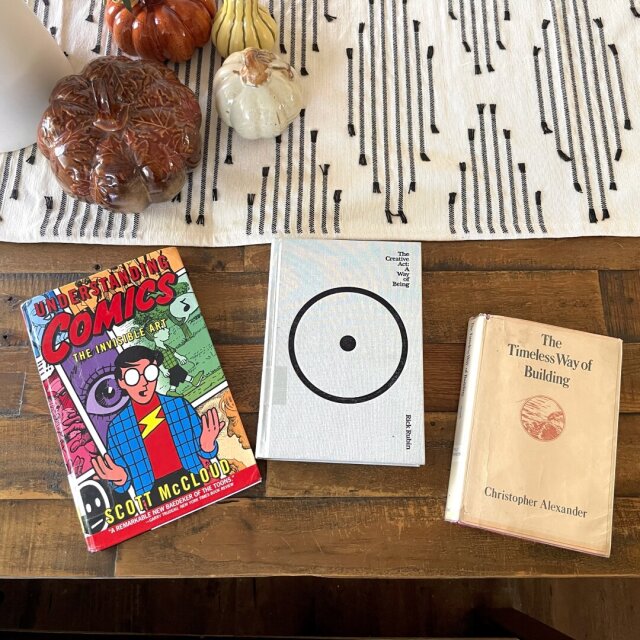 Three books laying on a wooden table top.