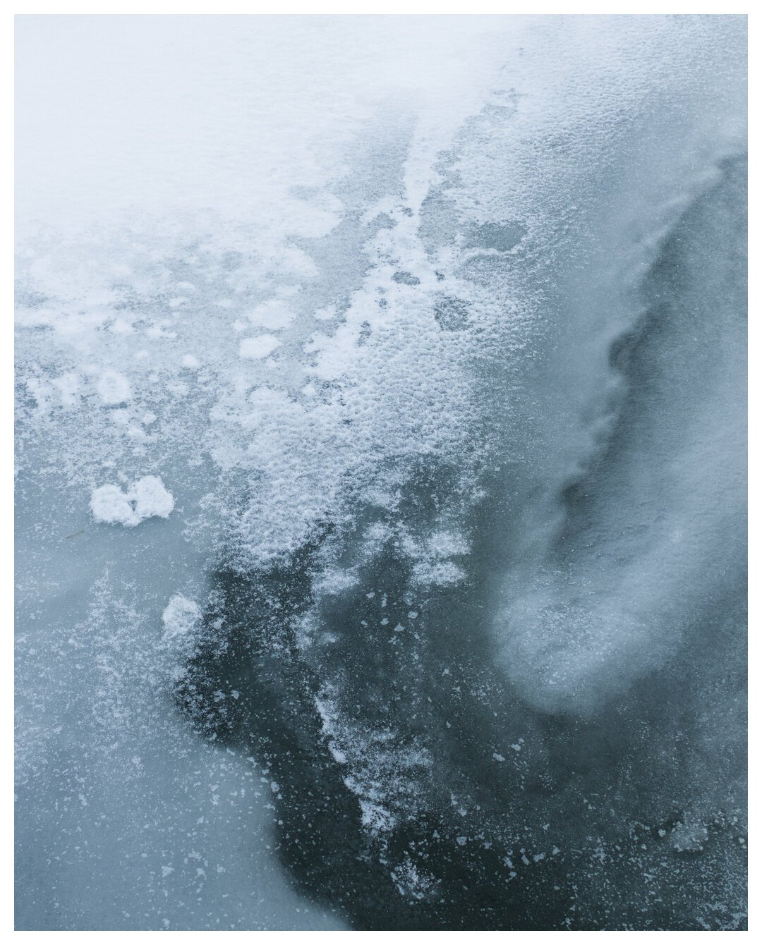 Snow and ice take up the entire frame, the dark of the river peaking through as a gradient. Cold vibes.