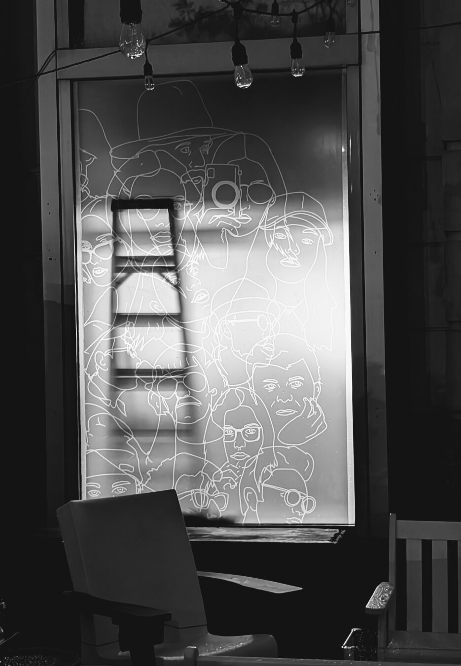 The silhouette of a ladder leaned up against an etched window, rendered in black and white