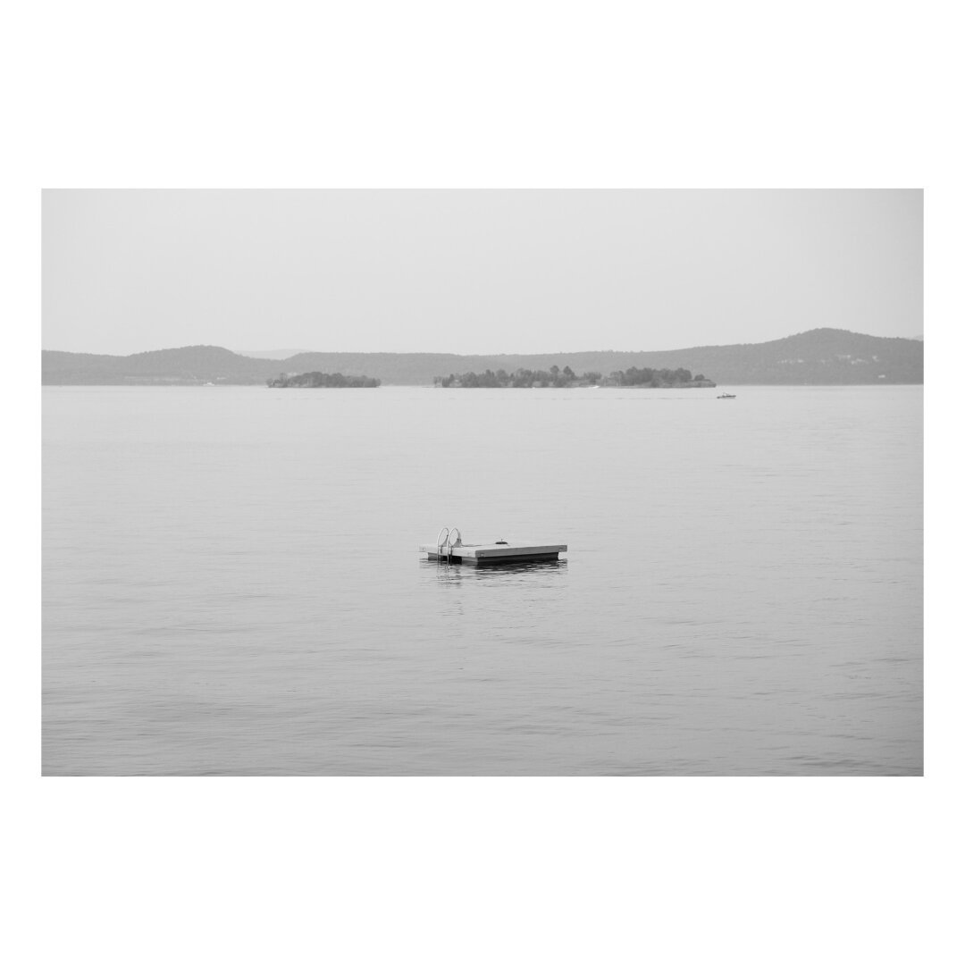 a single swim platform alone in an expansive lake with mountains in the background