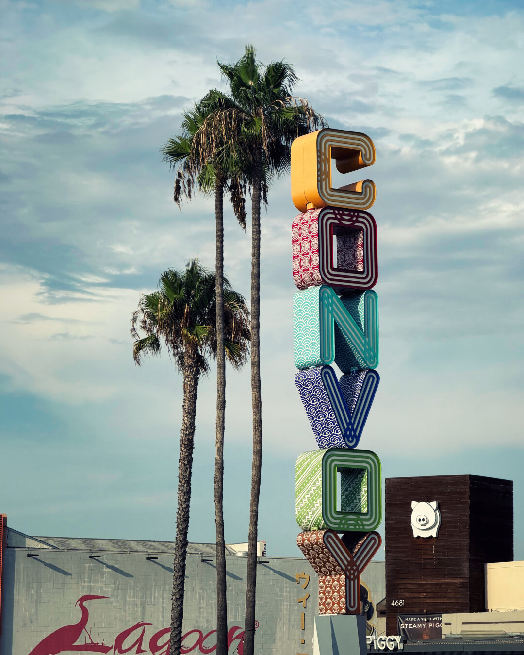 A colorful neighborhood sign that reads "Convoy." In the background, palm trees.