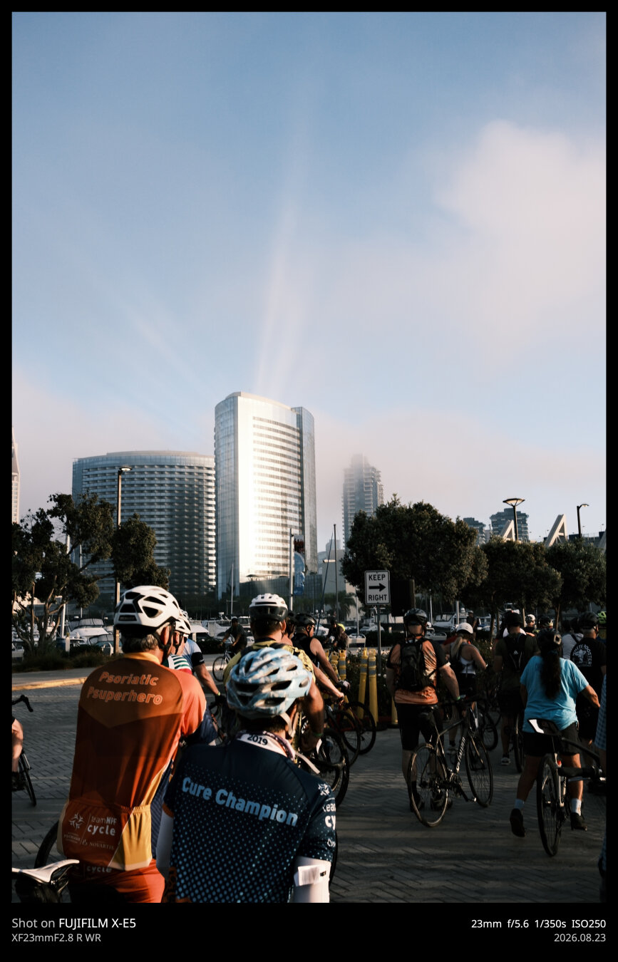 A different vantage point of the first photo. In this one, more of the bicyclists are illuminated by the morning light, both directly from the sun and from the reflection of the tower.