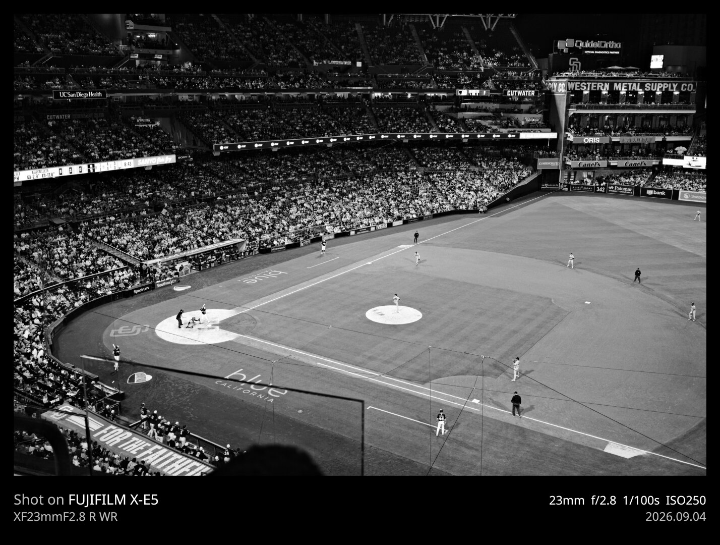 A black and white photo of Petco Park field. The image is dominated by the infield, with the stadium seats (mostly full) surrounding.