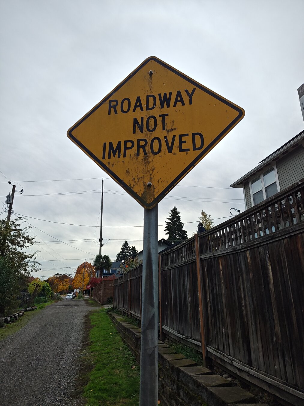 a road sign by a gravel alley which reads "roadway not improved"