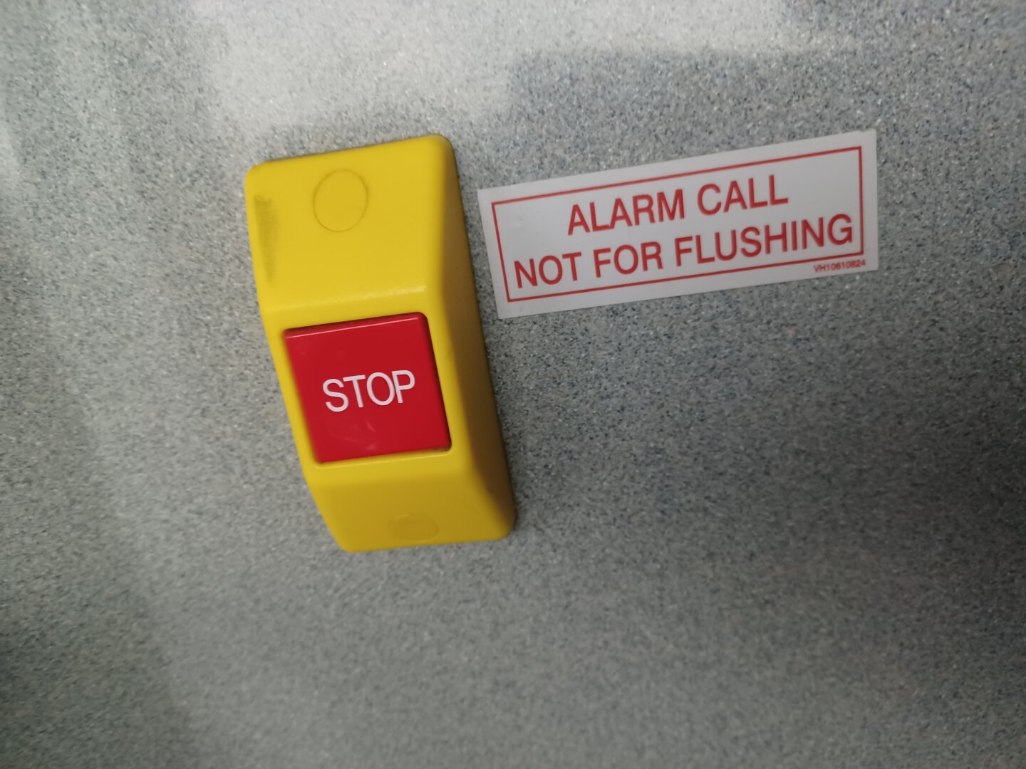 an emergency stop button in a bus bathroom that reads "ALARM CALL. NOT FOR FLUSHING"