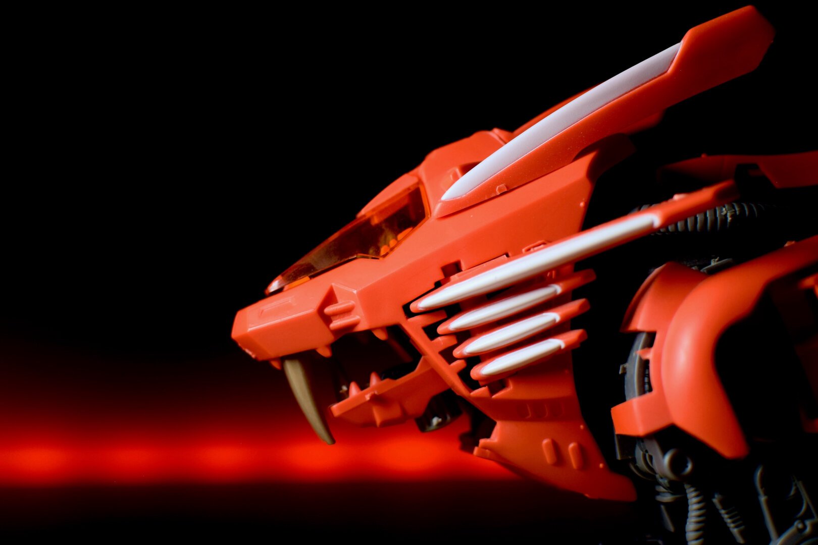 Close-up of a red toy robot lion with a dark background containing a red streak of light.