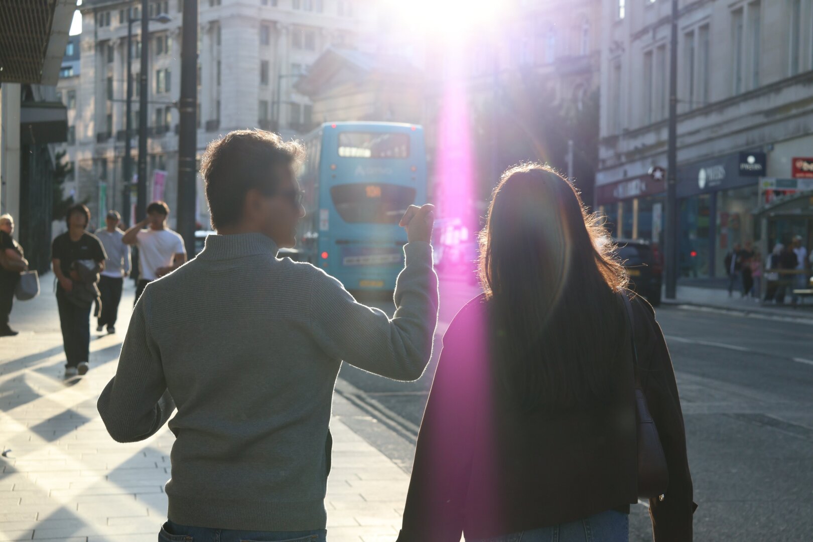A man walking down the street with a female. You can see the females hair visibly lit up by the sun and a lens flare covers her
