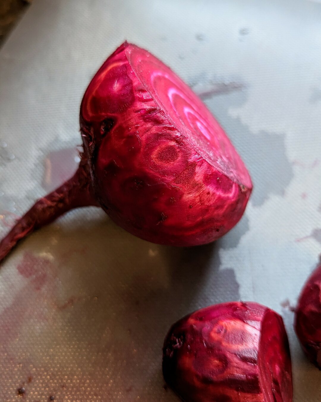 A beet with the top cut off that has striped patterns where the skin has been peeled off.