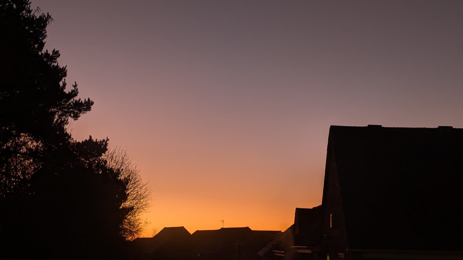 A red sky above the silhouettes of some houses
