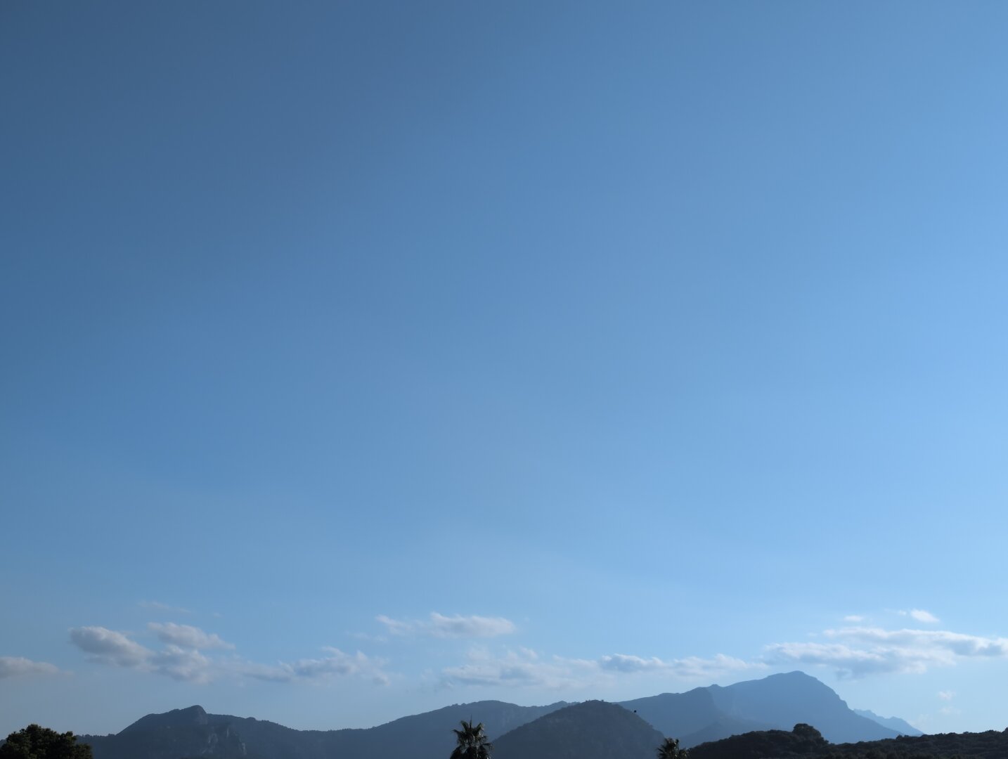 Blue sky above some hazy mountains