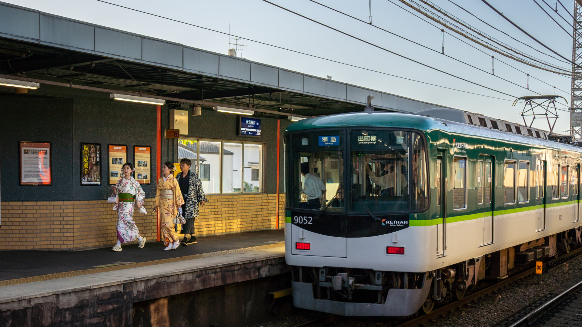 A train leaves the station. People walk on the opposite platform.