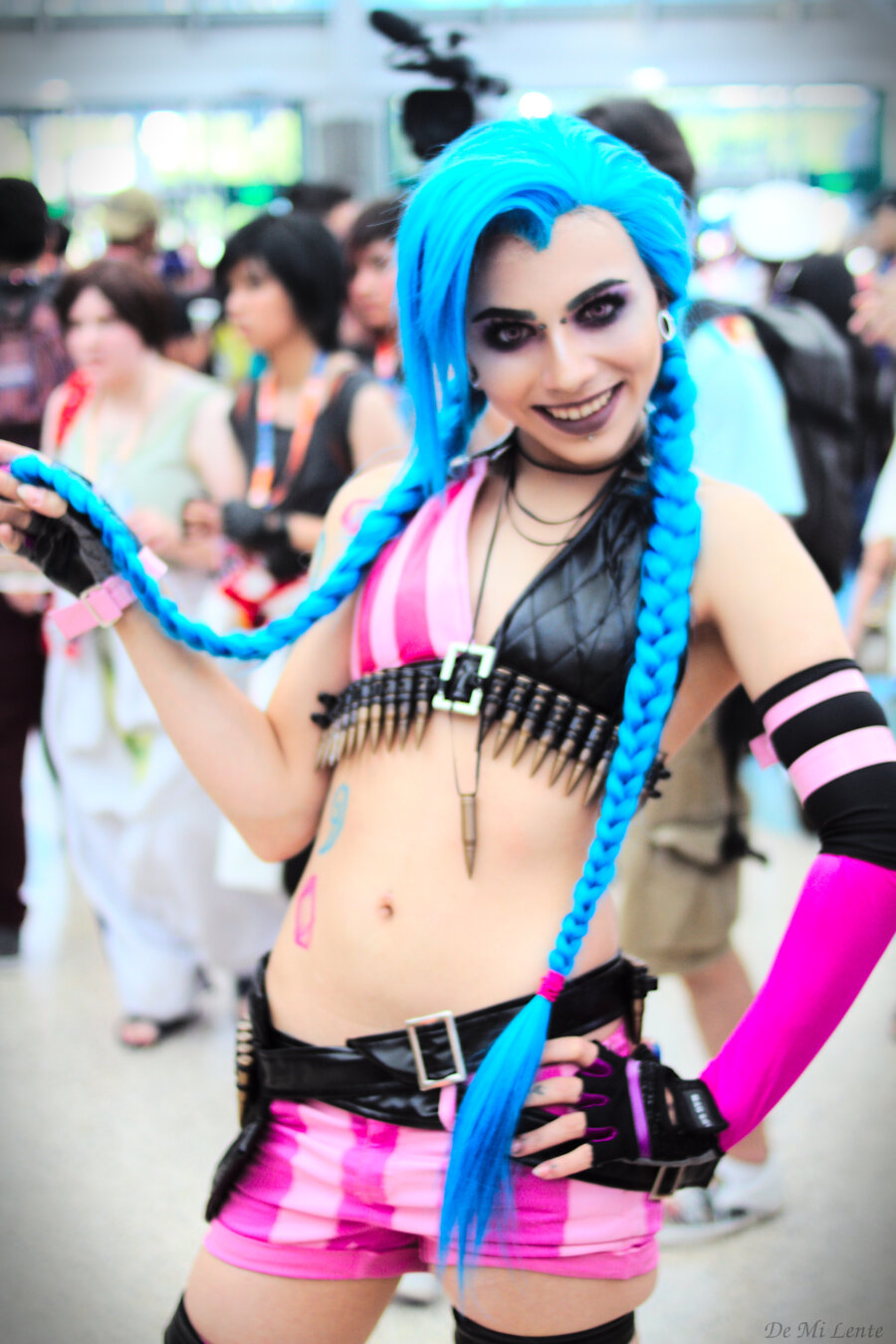 A young person as Harley Quinn at Anime Expo in Los Angeles California.  Long blue hair in pigtails.  Pink forearm sleelves.  A bikini top in black and red.