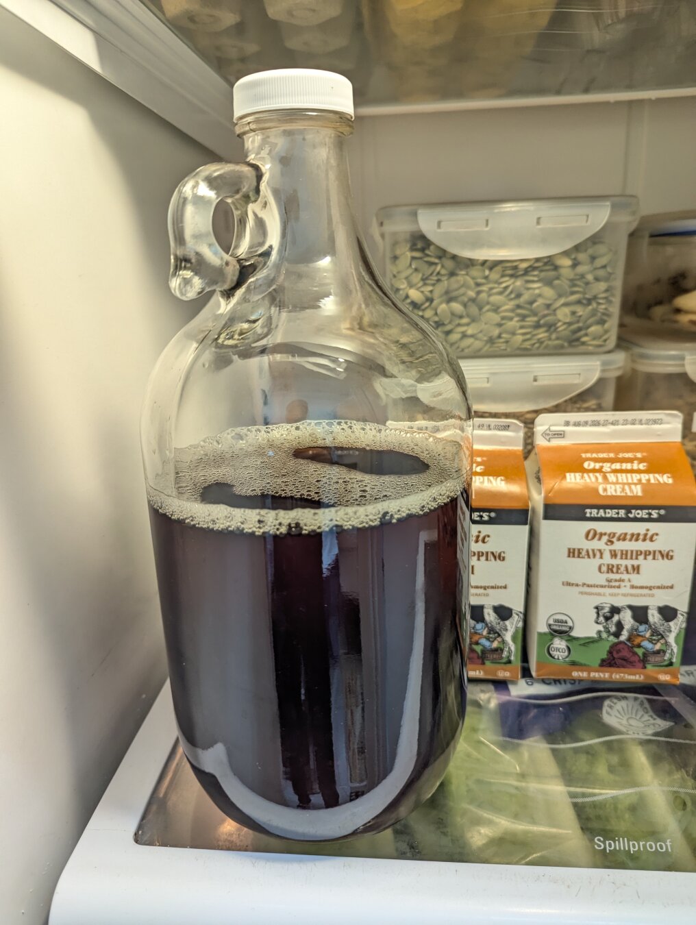 A glass jug full of very dark sun tea in the fridge.