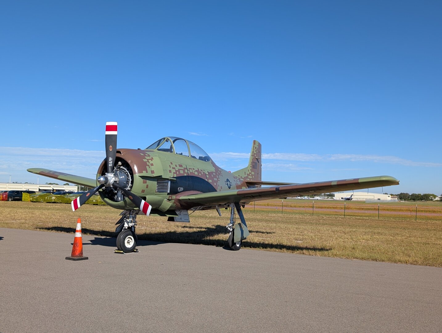 A North American T-28 Trojan airplane.  The livery is a green and brown digital camouflage.