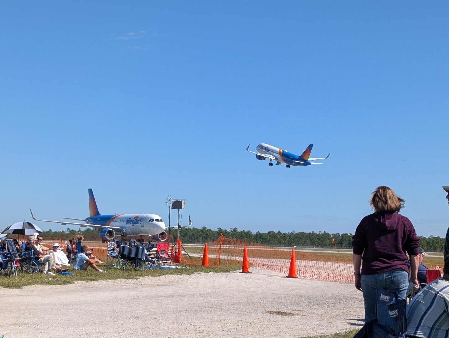 Two Airbus A320 family airliners operated by Allegiant Air. The one in the foreground had landed a couple of minutes earlier and is taxing to the terminal. The one in the background had just taken off moments ago.