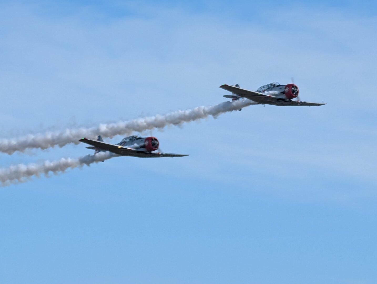 Two North American T-6 Texan airplanes in flight.  The planes are operated by Warbird Thunder.