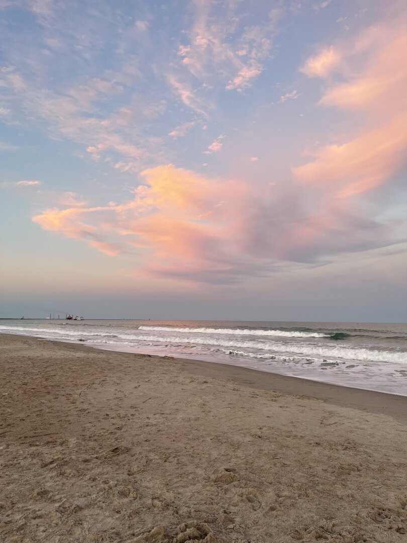 Beach surf under sunlit clouds