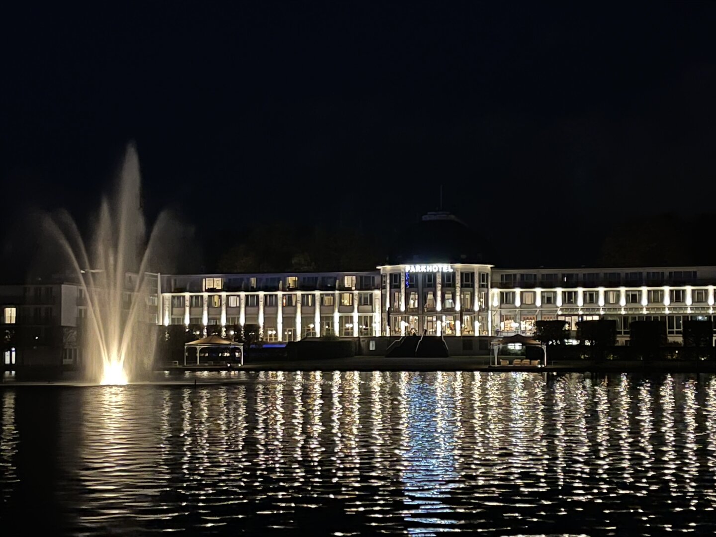 Night shot of the Park Hotel in Bremen. Illuminated, mirrored in the Hollersee with an illuminated fountain