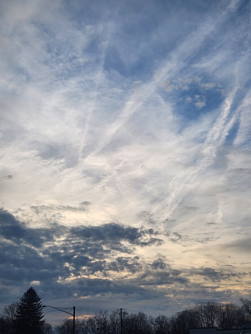 Sun setting in the clouds above trees