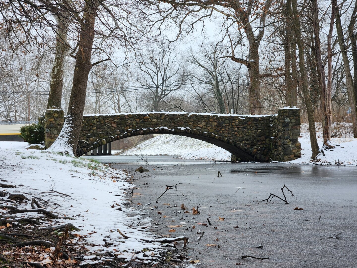 Stone bridge on a half frozen pond in the snow