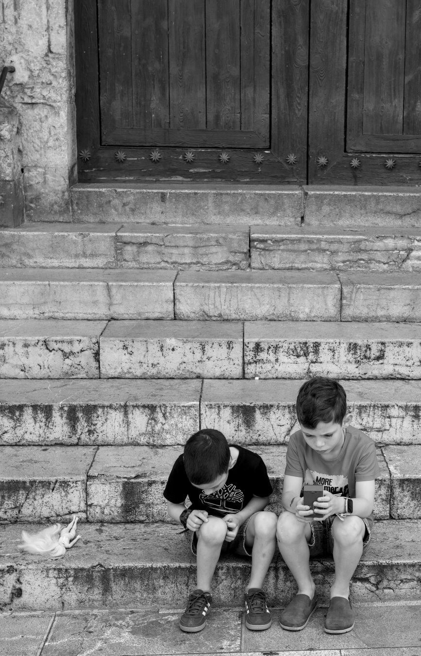 Two young kids sitting in a stair.