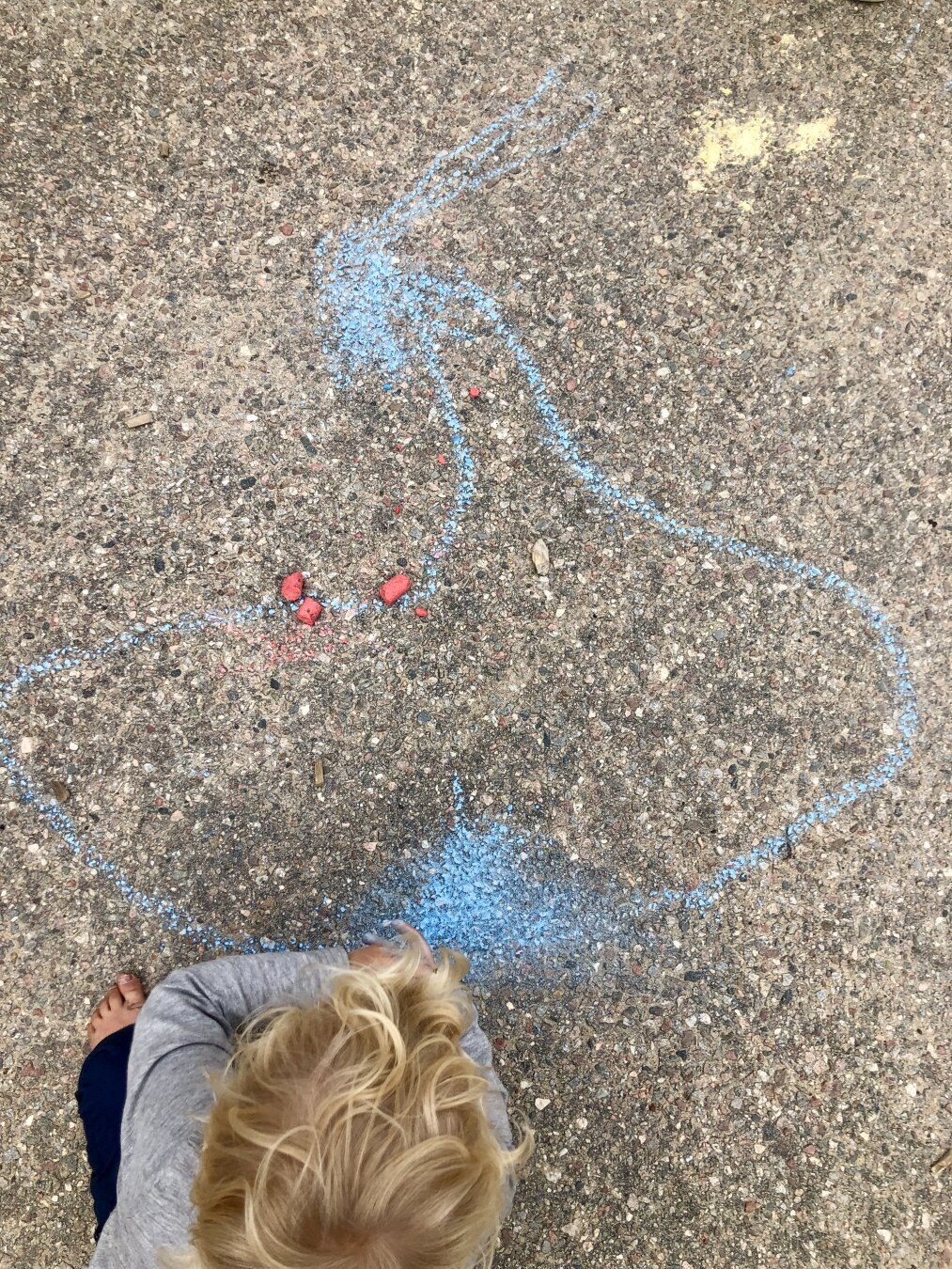 A blue street chalk silhouette of what vaguely resembles a sailboat.