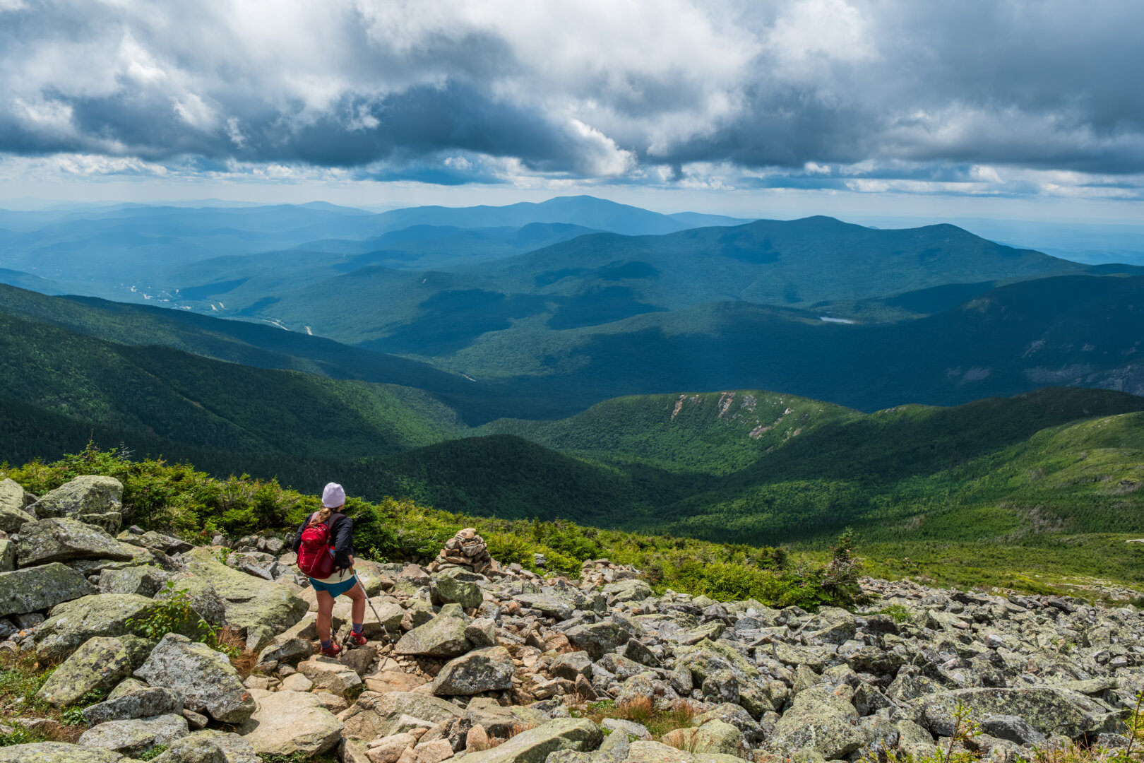 A hiker stands among the rocks above the treeline and looks out across the south end of Franconia Notch. It's a cloudy day with occasional showers in the distance.
© Tom Goetz. All rights reserved. Training an AI on this image is expressly forbidden.