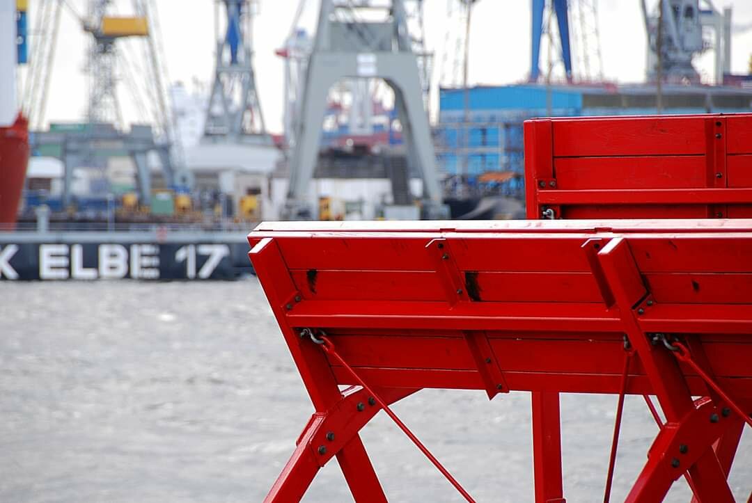 Part of a red paddle steamer, with the docks of the Port of Hamburg, Germany in the background.