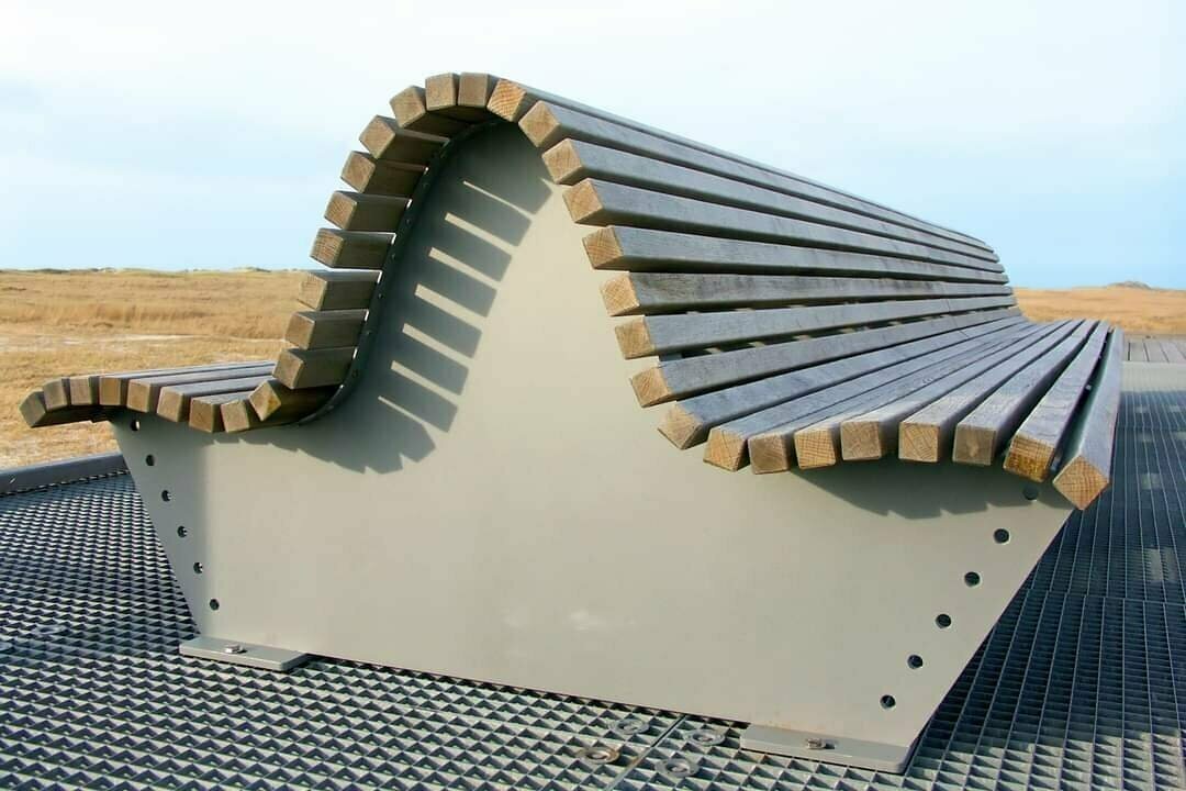 Double-sided curved bench on a pedestal on the beach.
