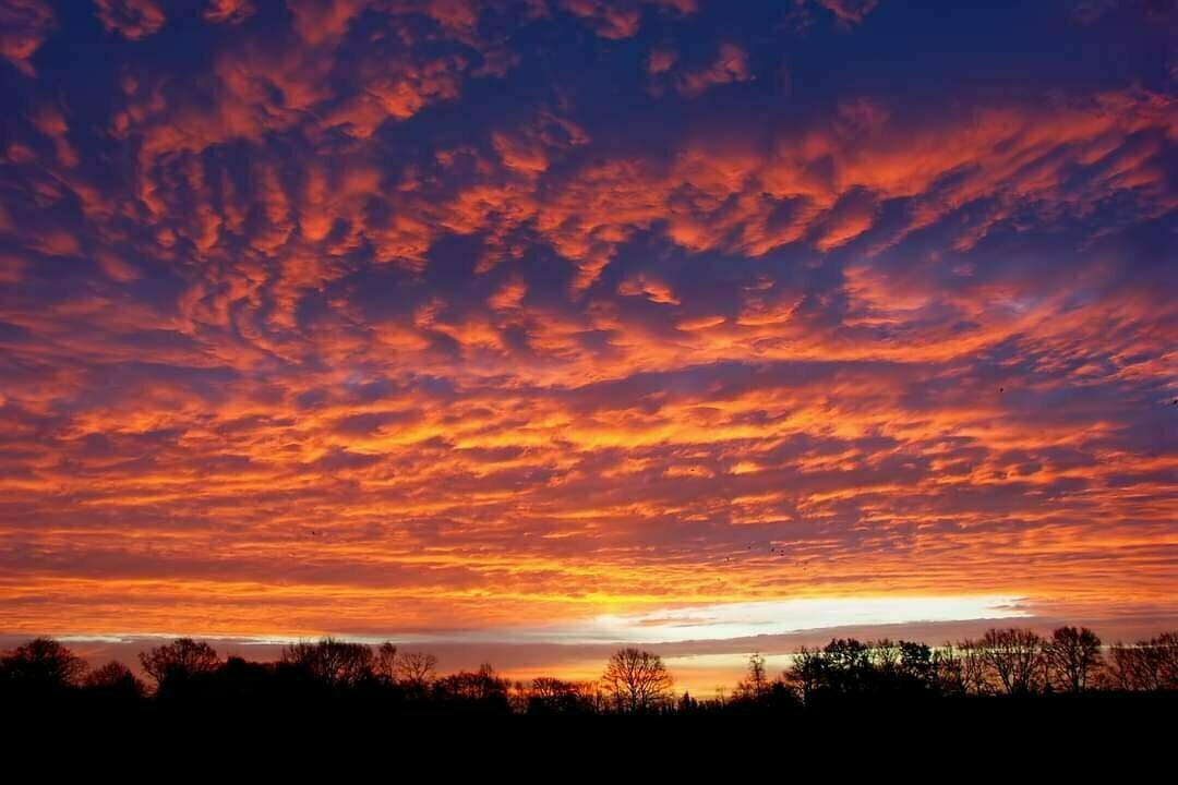 Colorful sunrise with clouds panorama above the silhouette of the horizon.