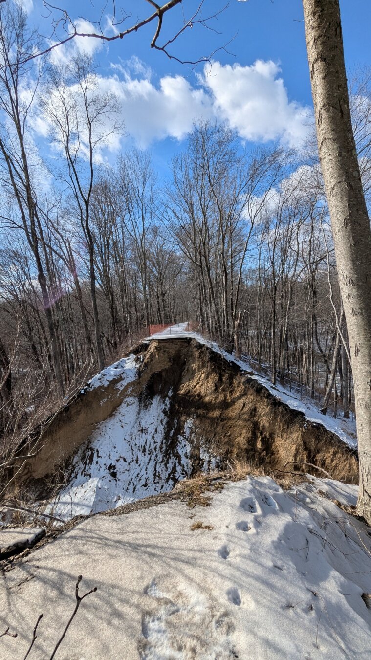 Flood damage to the Bridle Trail from above, showing a large gap where the trail has been washed away.