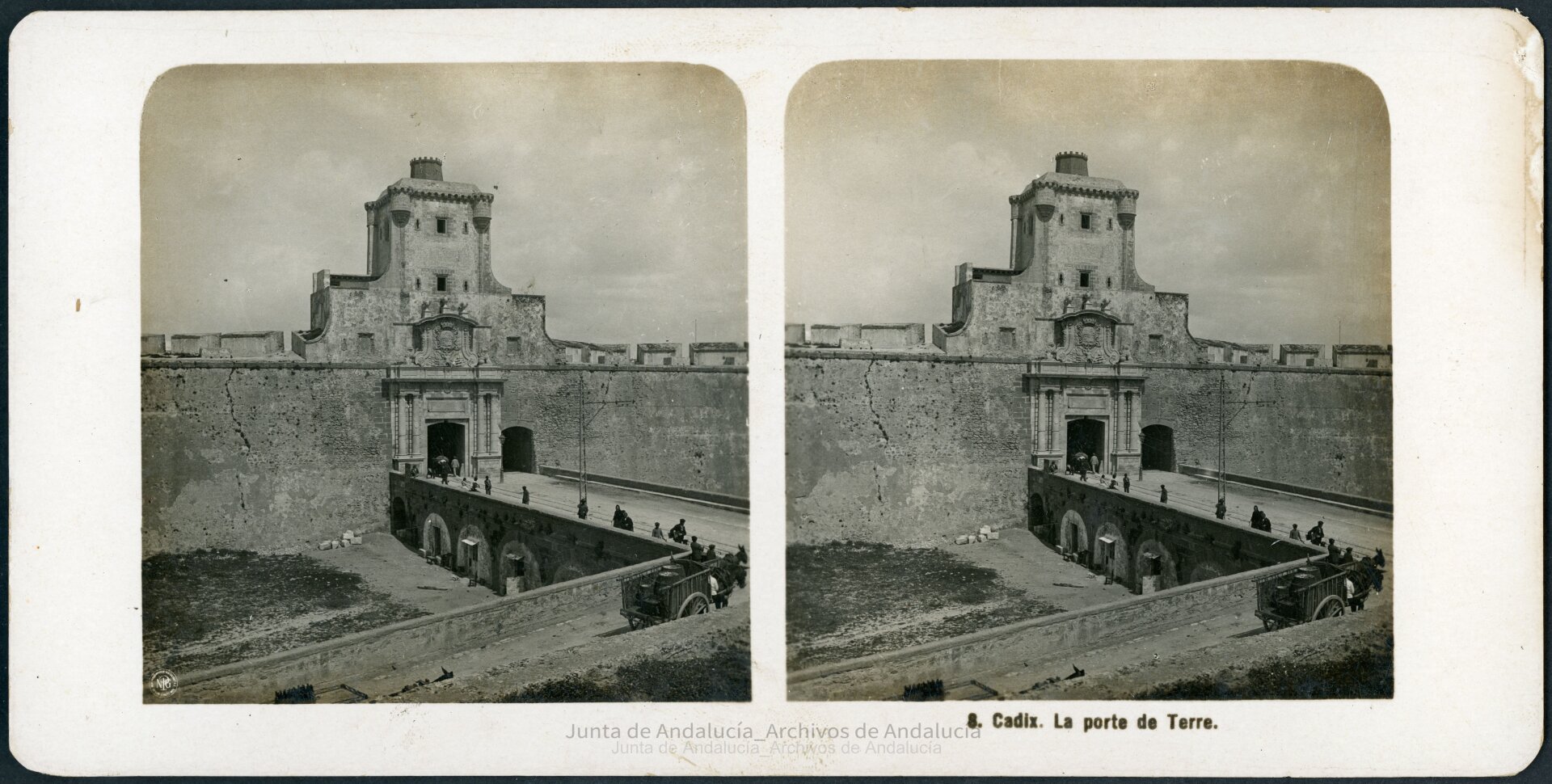 Muralla con dos entradas contiguas de distinto tamaño. Por la mayor salen las vías del tranvía, que pasan por un puente.