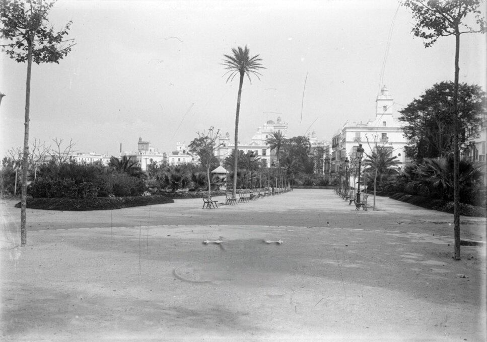 Paso amplio con zonas ajardinadas con árboles. Tiene un camino central con dos hileras enfrentadas de bancos de madera que alterna con árboles pequeños y farolas.