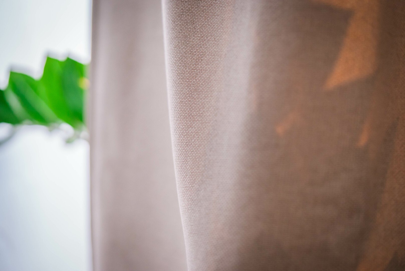 A close-up of the fabric of a sand-coloured curtain. The texture of the fabric is in focus