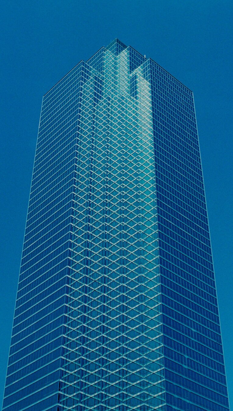 a blue building against the blue sky. It's made of glass and the windows form a crisscross geometric pattern.