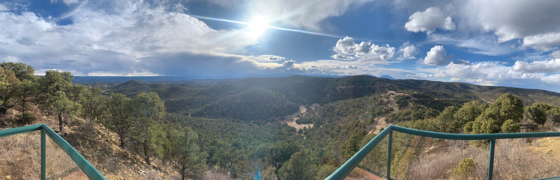 A panorama Picture showing a mountain range and slightly cloudy sky from a balcony on a mountaintop